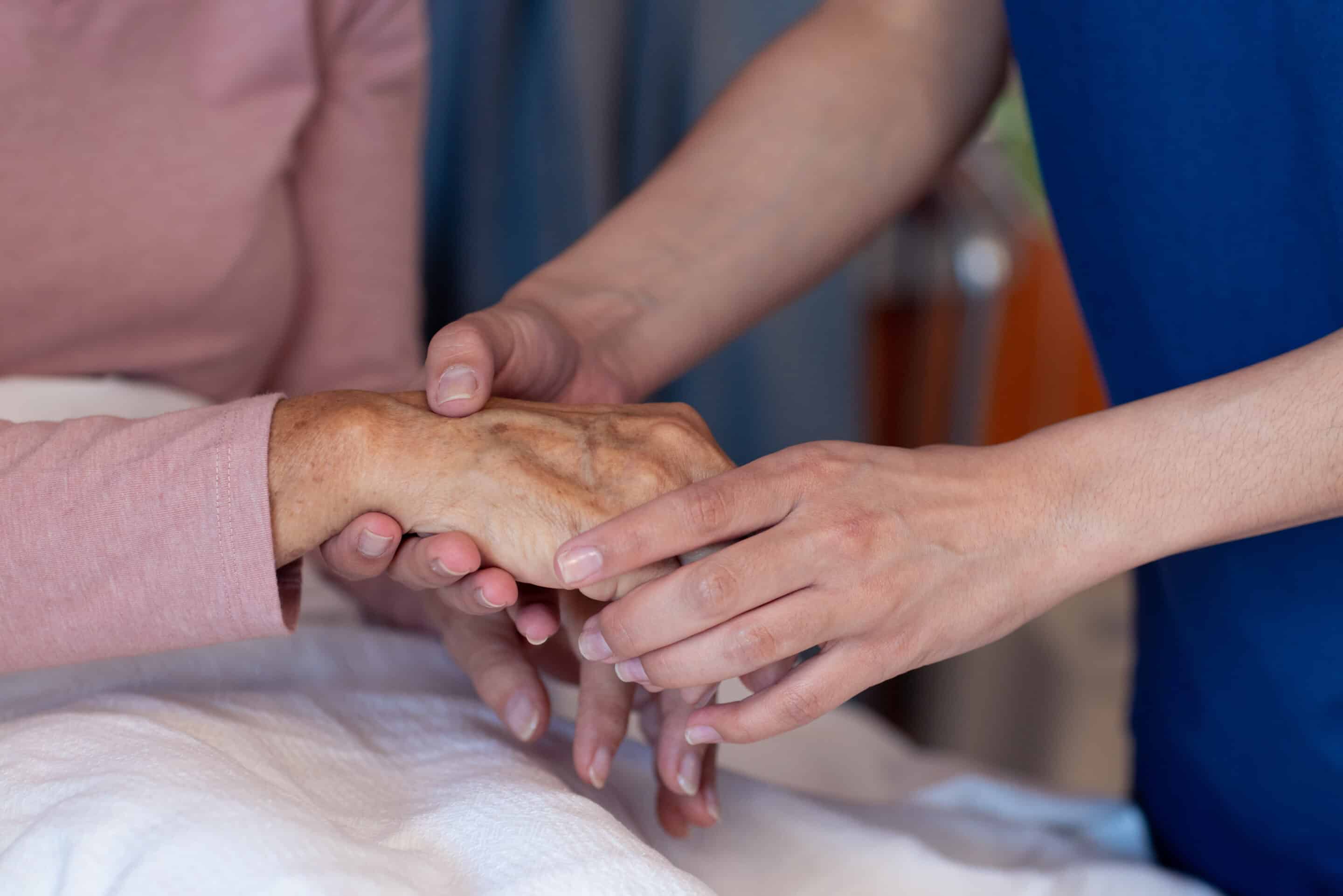 Woman holding elderly persons hands