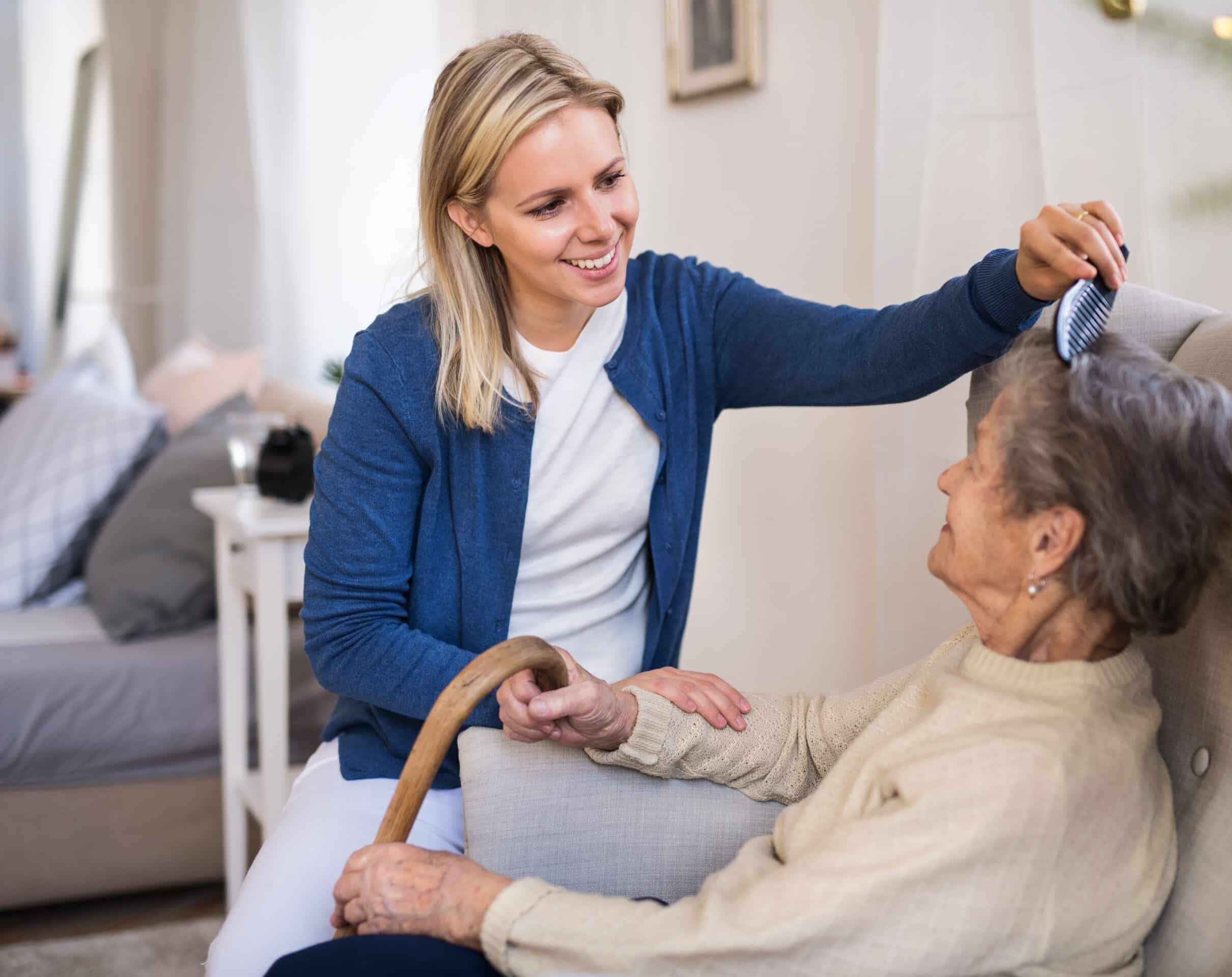 A health visitor combing hair of senior woman at home