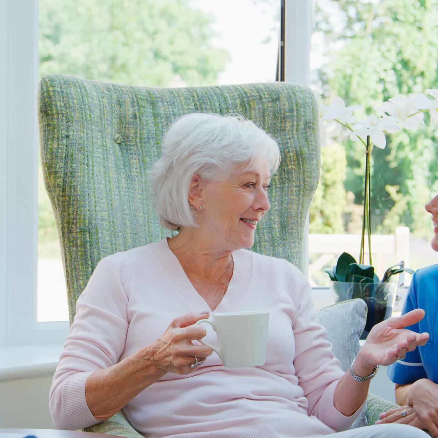 Senior Couple Sitting In Chair And Talking With Carer